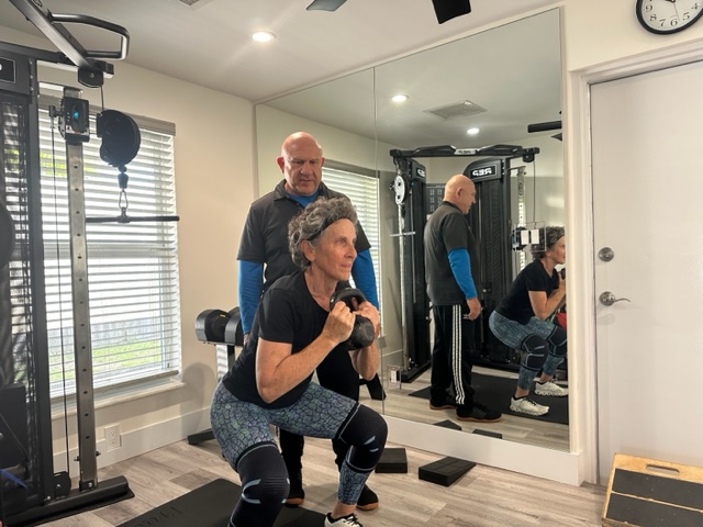 Woman squatting with kettlebell, personal trainer.